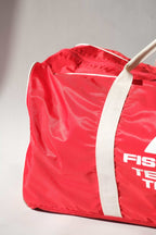 Detailed macro shot  of a vintage red Fischer Tennis Team sports duffle bag featuring white logo and bold text.