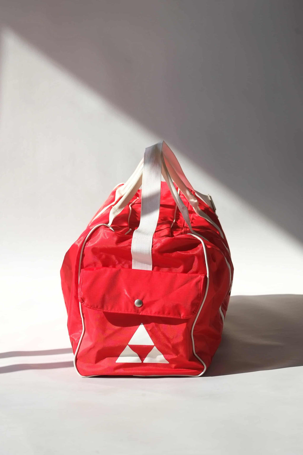 end pocket view of a vintage red Fischer Tennis Team sports duffle bag featuring white logo and bold text.
