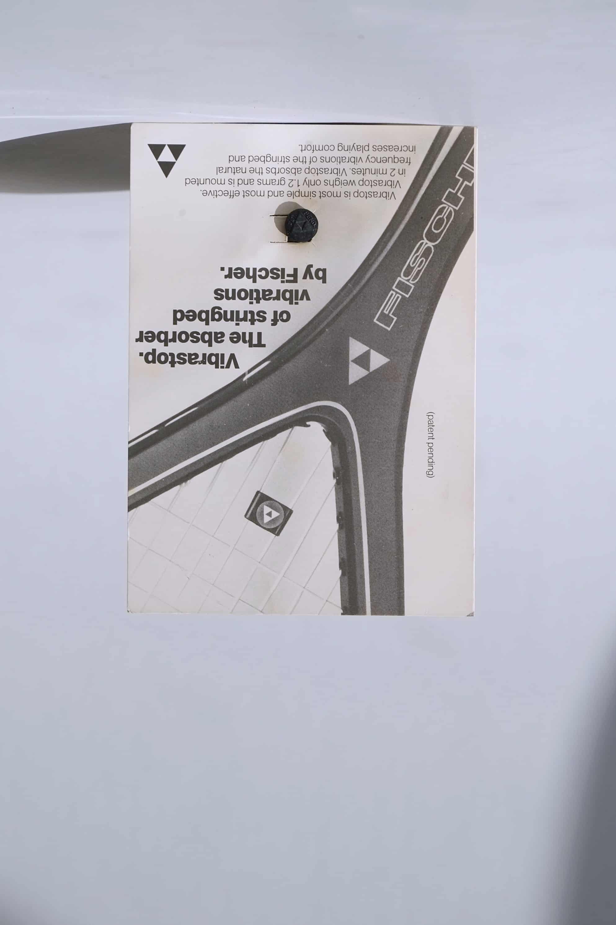 Deadstock vintage Fischer Vibrastop tennis stringbed vibration dampener, displayed on its original retail card featuring retro branding.