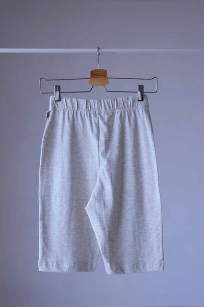Back shot of a pair of Heather oatmeal Fruit of the loom  Ladies Wear biker shorts hanging on a hanger. The shorts have an elastic waistband and are made of a soft, stretchy fabric.