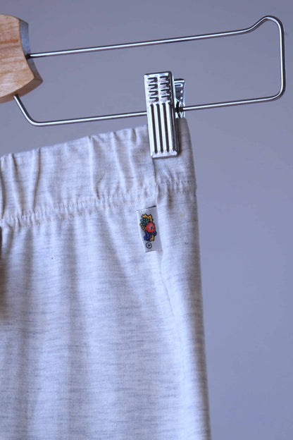 Close-up of heather beige Ladies Wear biker shorts hanging on a wooden hanger. The waistband of the shorts is visible, with the tag showing a label with a small fruit illustration.