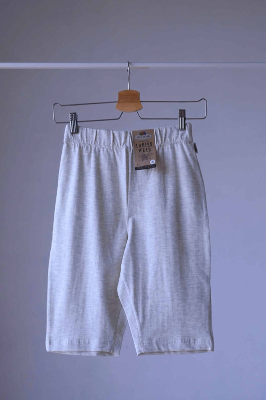 Heather oatmeal Fruit of the loom  Ladies Wear biker shorts hanging on a hanger. The shorts have an elastic waistband and are made of a soft,
 stretchy fabric. The tag is visible on the waistband.