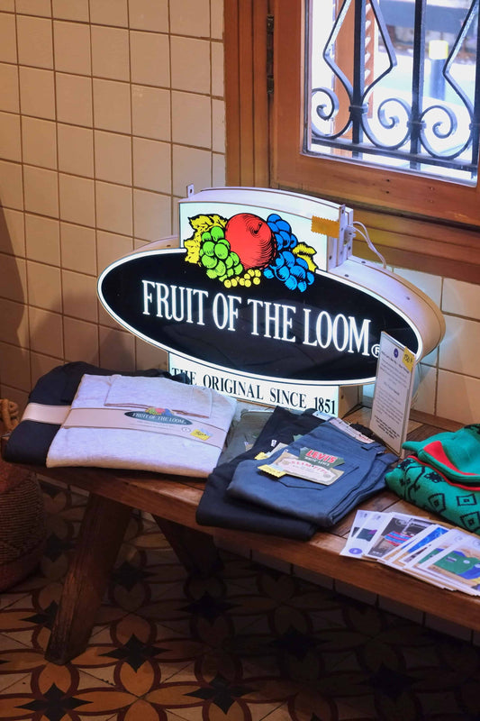 Vintage Fruit of the Loom light-up store sign with the 1978-2003 logo, displayed in a vintage shop setting.
