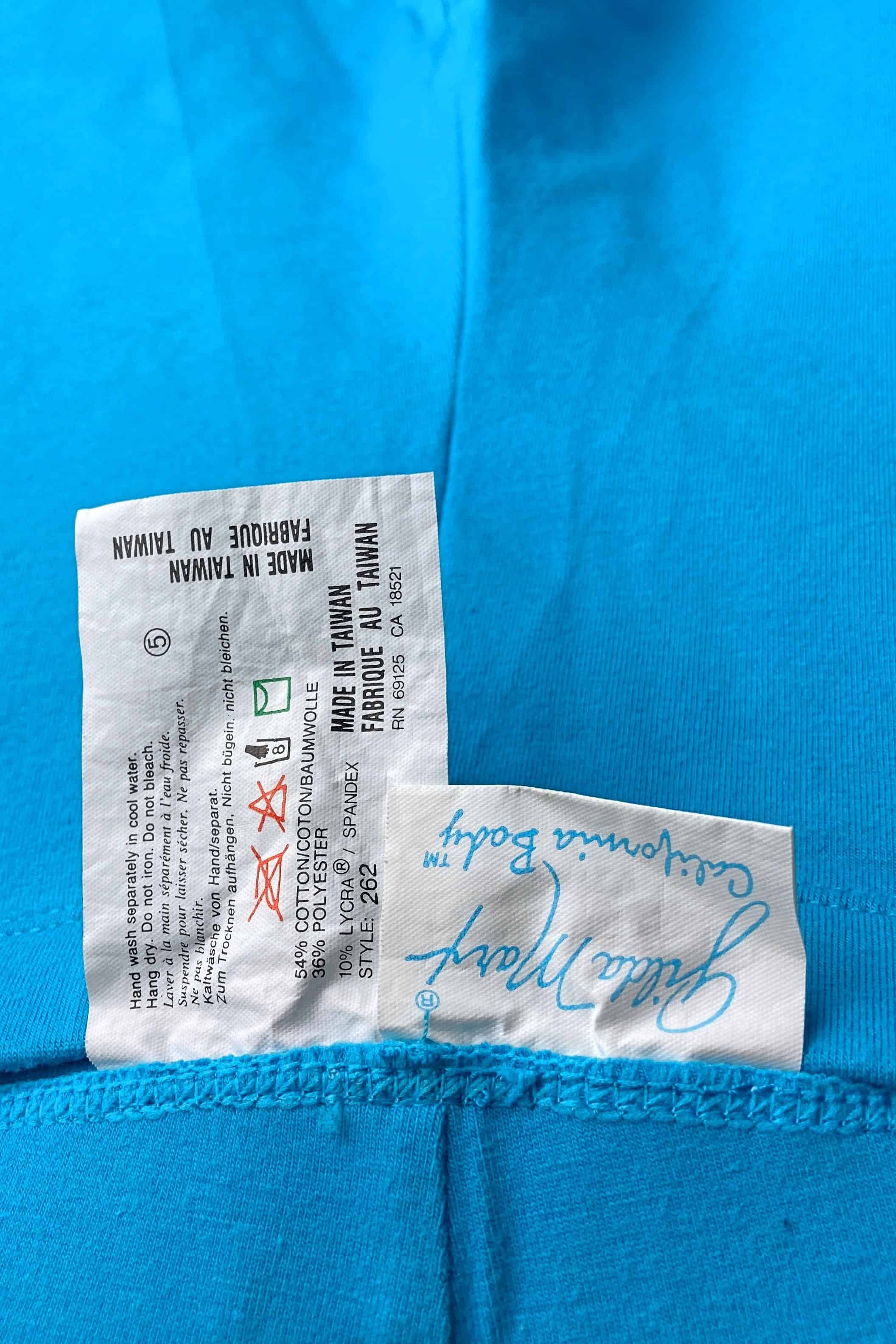 A close-up of the brand and care tag on a pair of blue vintage GILDA MARX leggings, showing the logo and fabric content.