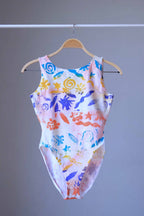 Front view of a vintage Gilda Marx leotard with an abstract beach-themed pattern on a hanger.