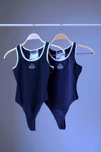 Two black KAPPA vintage 90s women's activewear leotards, one dark navy and one black, with white trim and chest logos, displayed side-by-side on hangers.