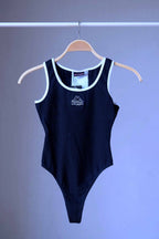 Front view of a black KAPPA vintage 90s women's activewear leotard with white trim and a chest logo, displayed on a wooden hanger.