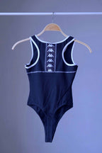 Back view of a navy KAPPA vintage 90s women's activewear leotard with white trim and a chest logo, displayed on a wooden hanger.