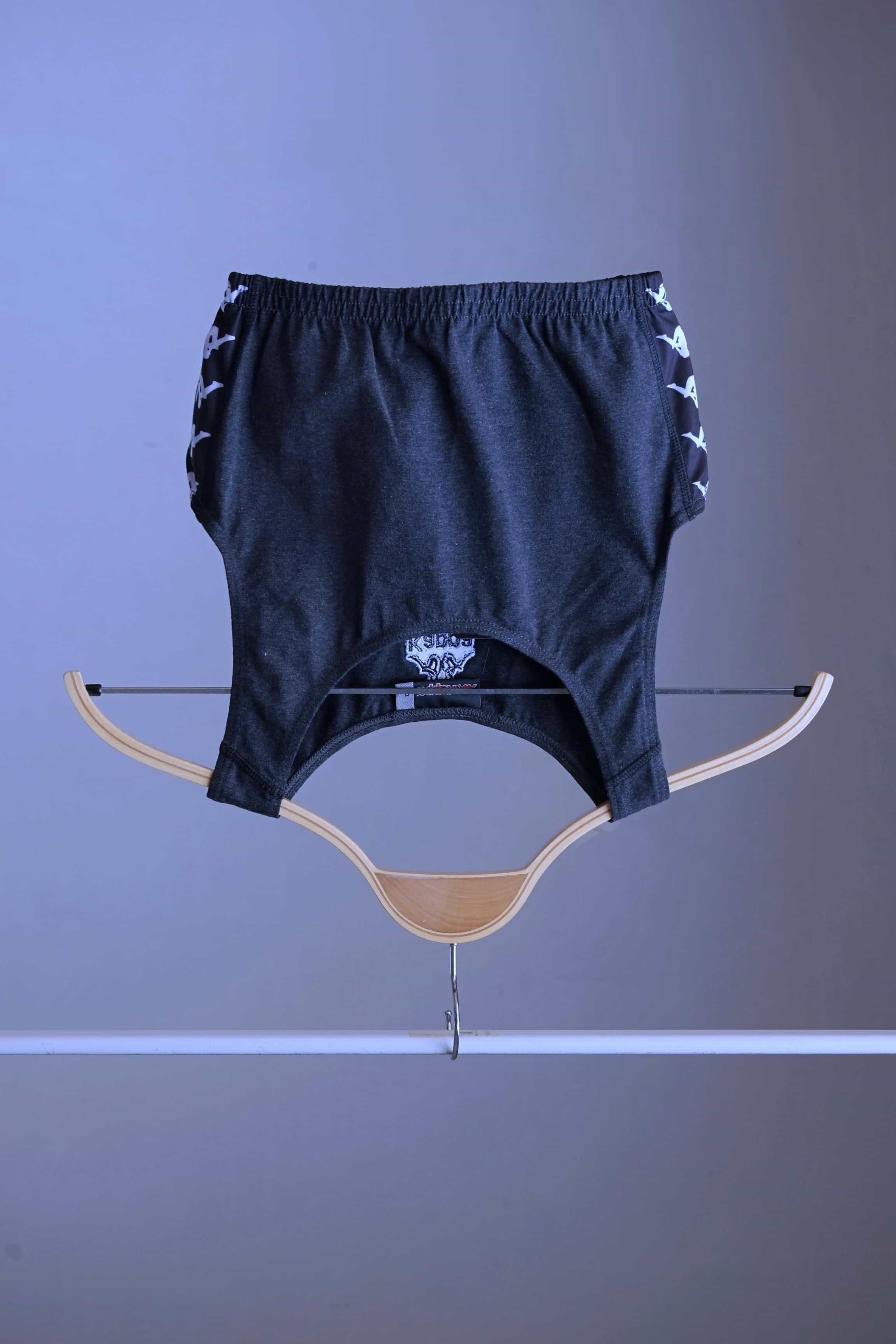 Front view of a charcoal grey KAPPA vintage women's athletic crop top on a wooden hanger, showing the KAPPA logo on the front and white logo taping along the sides.