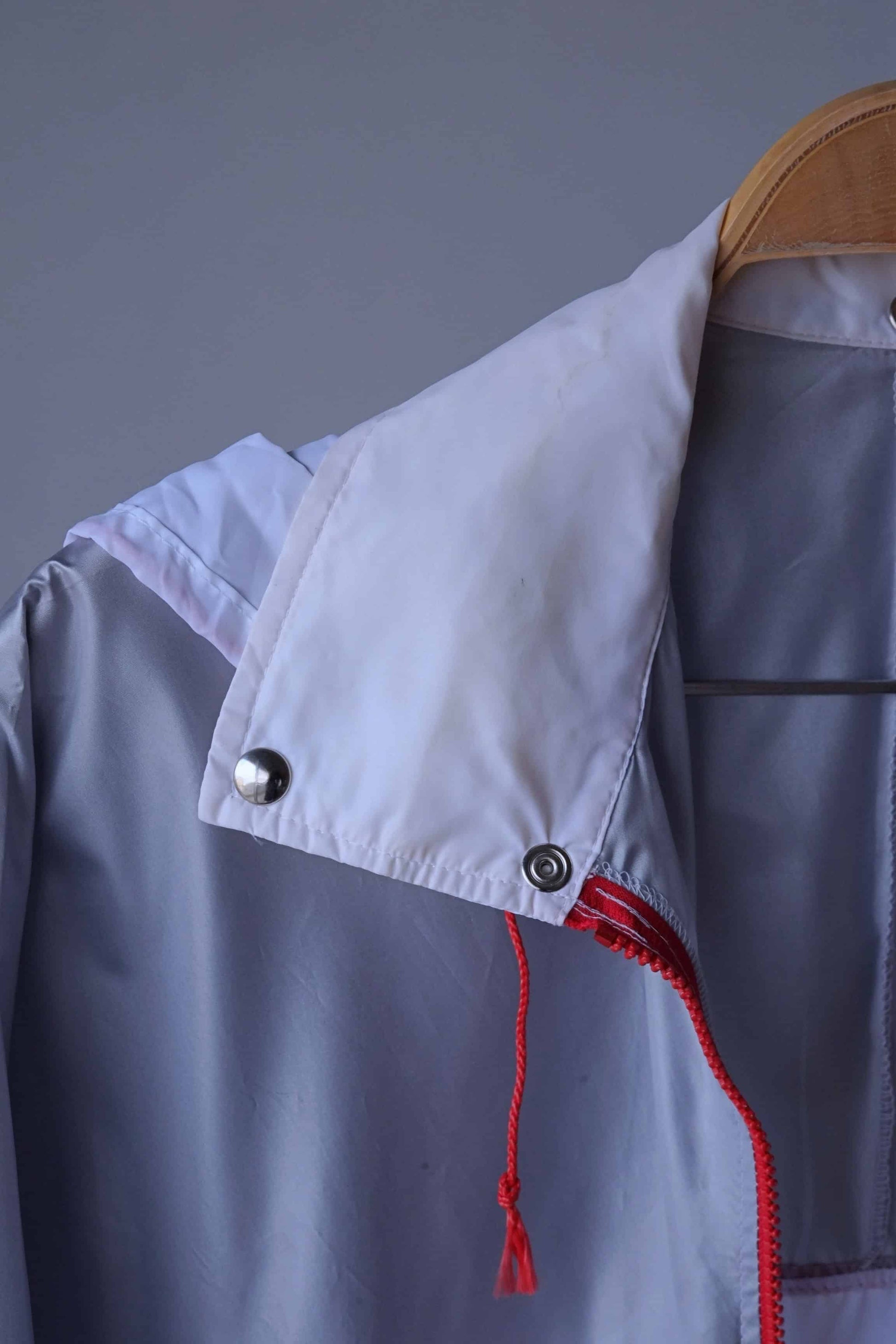 Close-up of the collar and hood of a vintage Koflach windbreaker jacket. The jacket has a white collar with some light staining and a red drawstring hood.