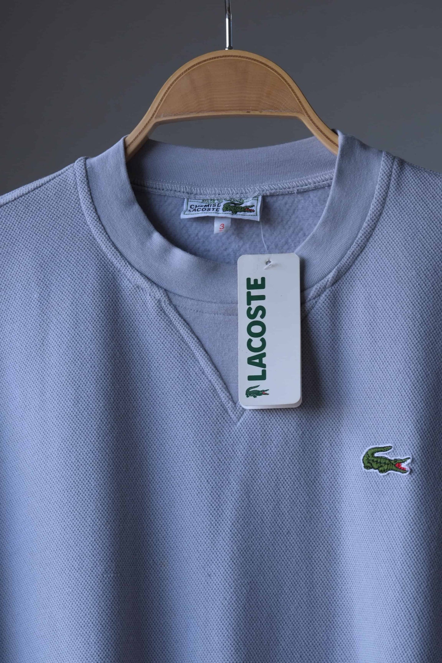 close up of Gray Lacoste 90s sweatshirt on hanger showing the tag