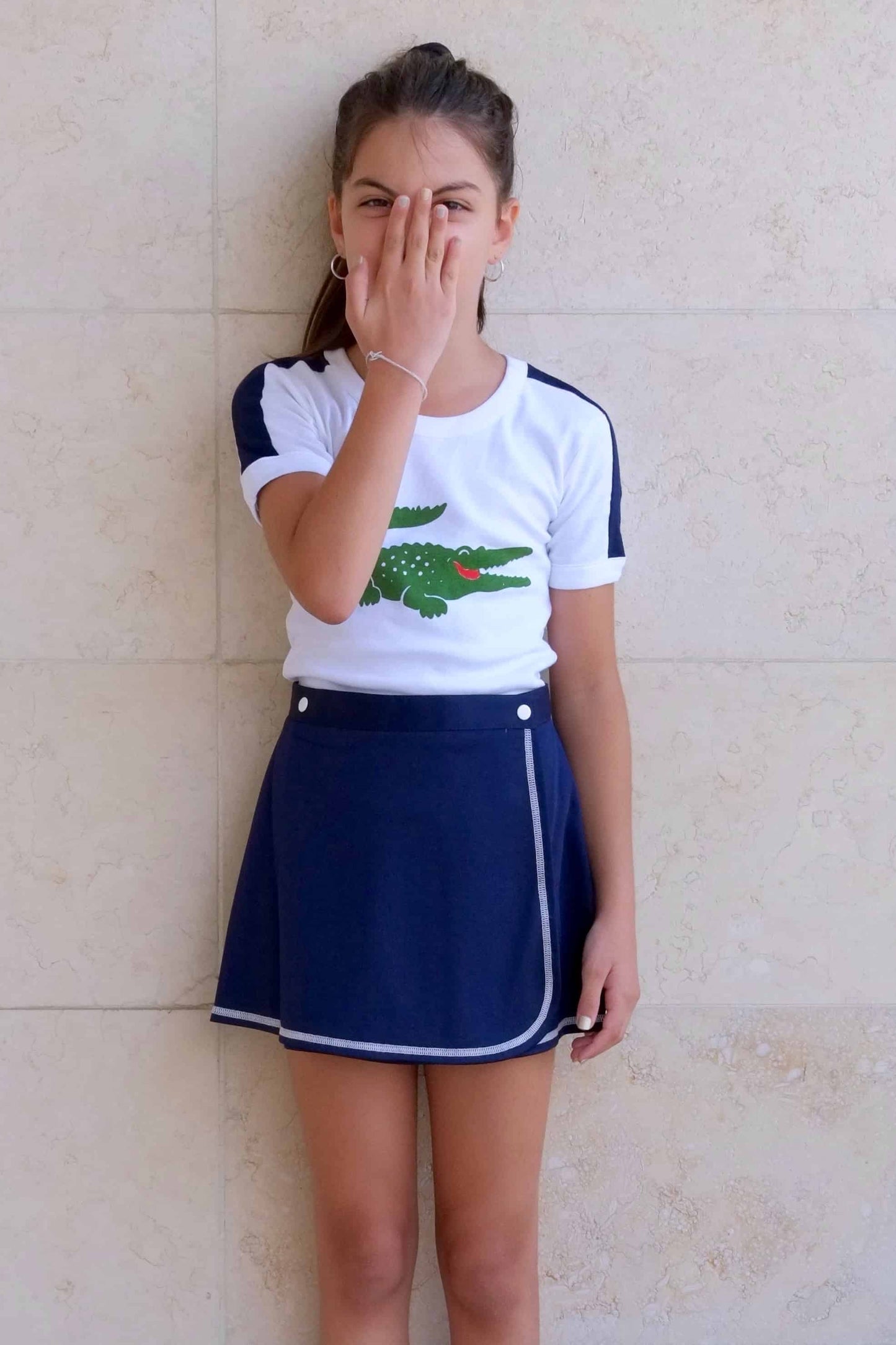 LACOSTE Crocodile Logo T-shirt in white modeled on girl in navy skirt 
