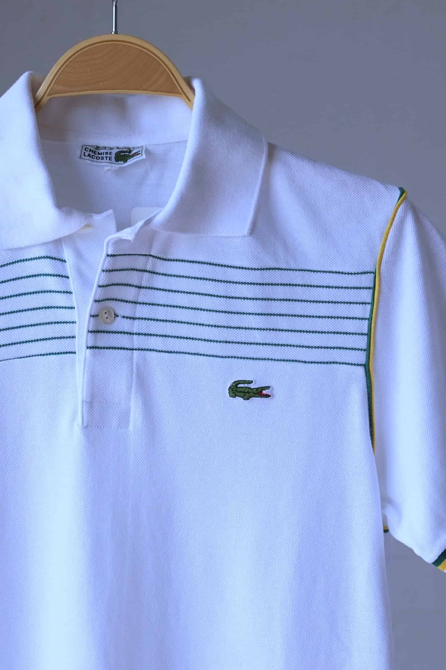 close up of LACOSTE Retro Polo in white with yellow stripes and green edging photographed on hanger