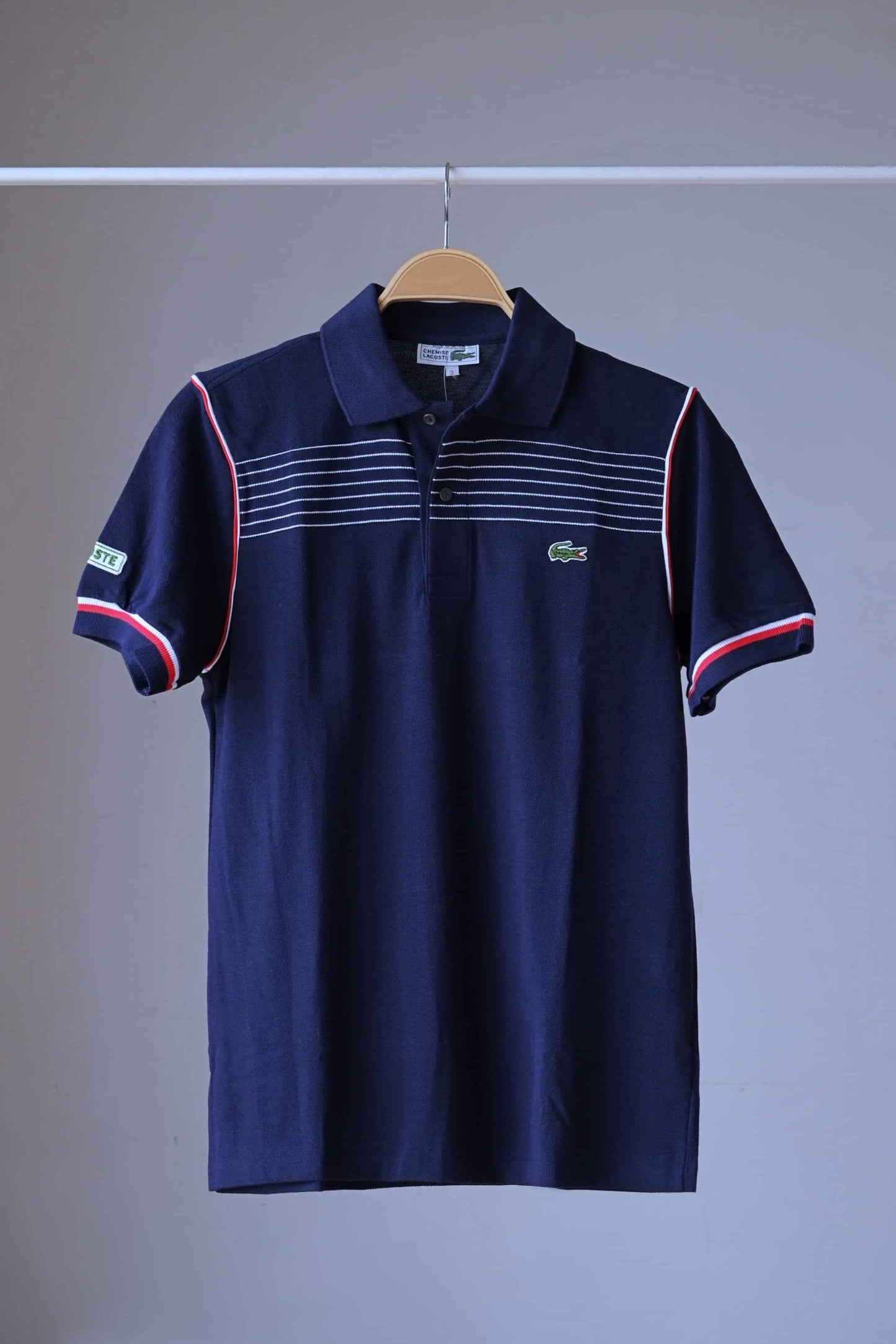 LACOSTE Retro Polo navy with white stripes and red edging photographed on hanger