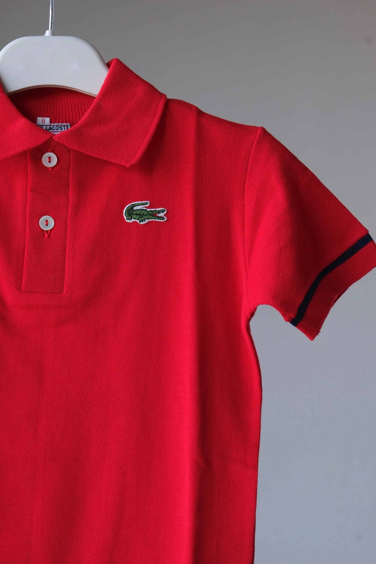 close up of LACOSTE Vintage Kids Polo in red with a navy line on the armband
