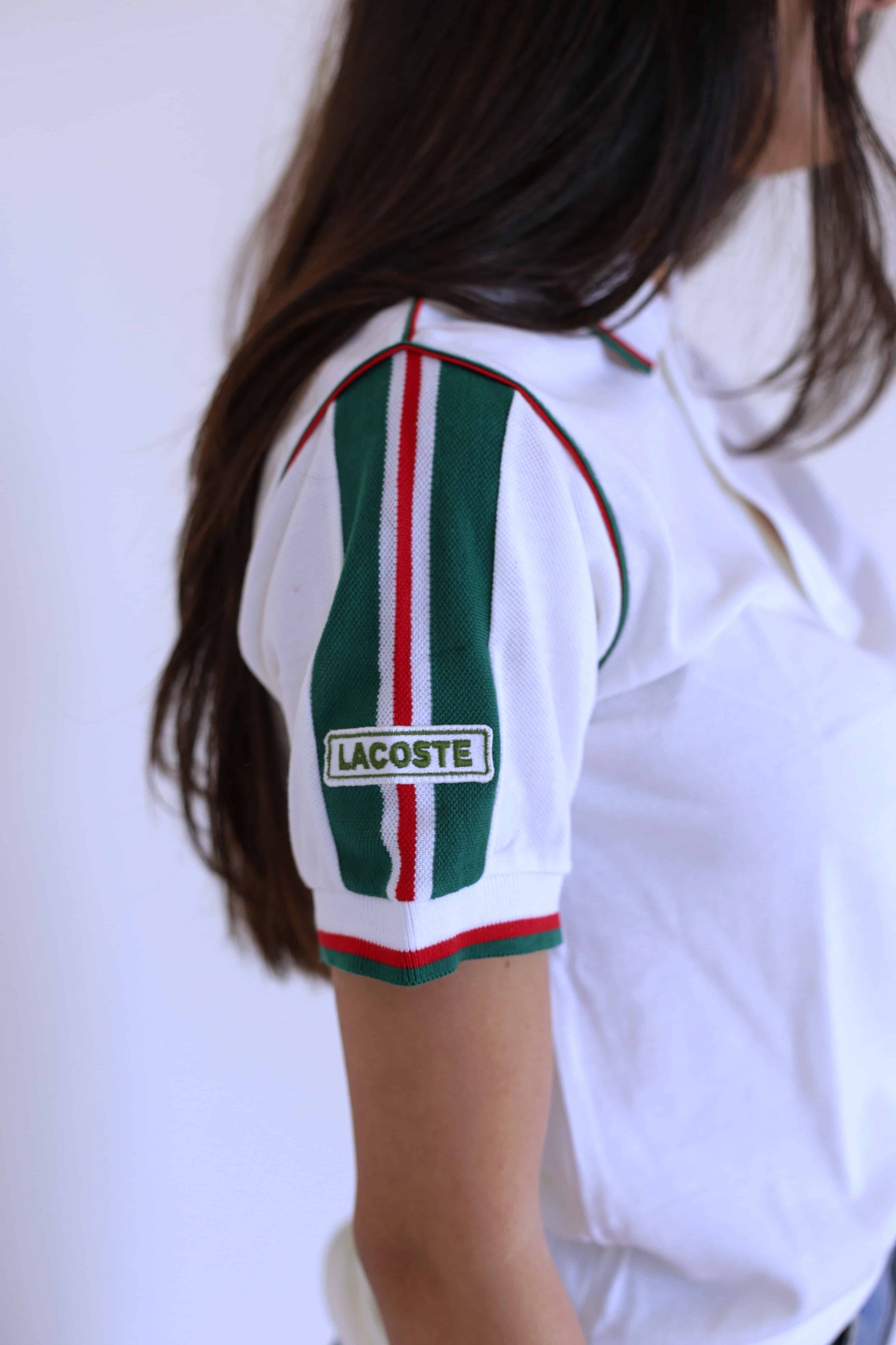 Lacoste vintage shirt in white with green stripes on the sleeves and the Lacoste logo showing, on model 