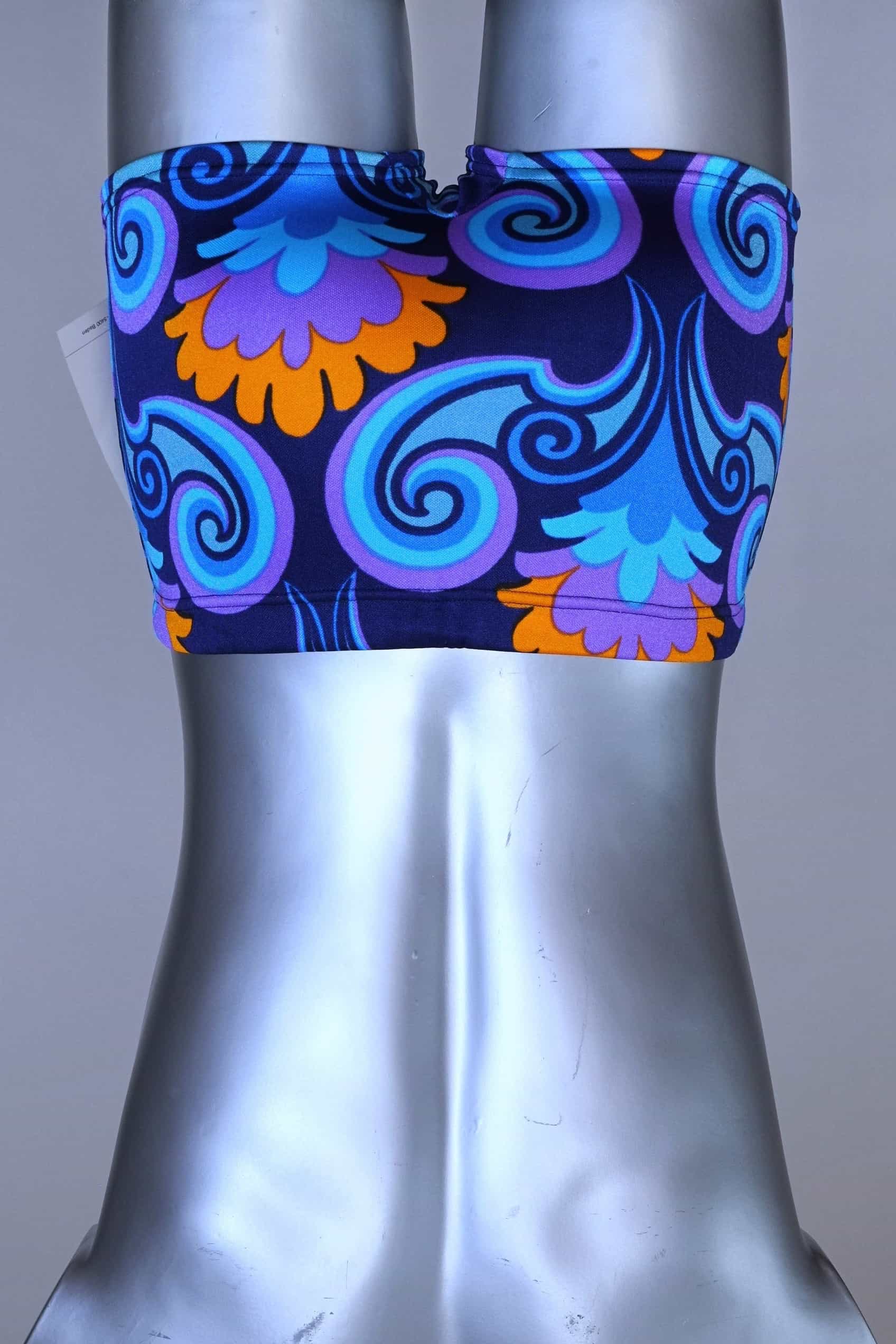 Back view of LAHCO vintage 60s square-cut swim trunks in a blue, purple, and orange psychedelic floral print, shown on a mannequin with original tag.