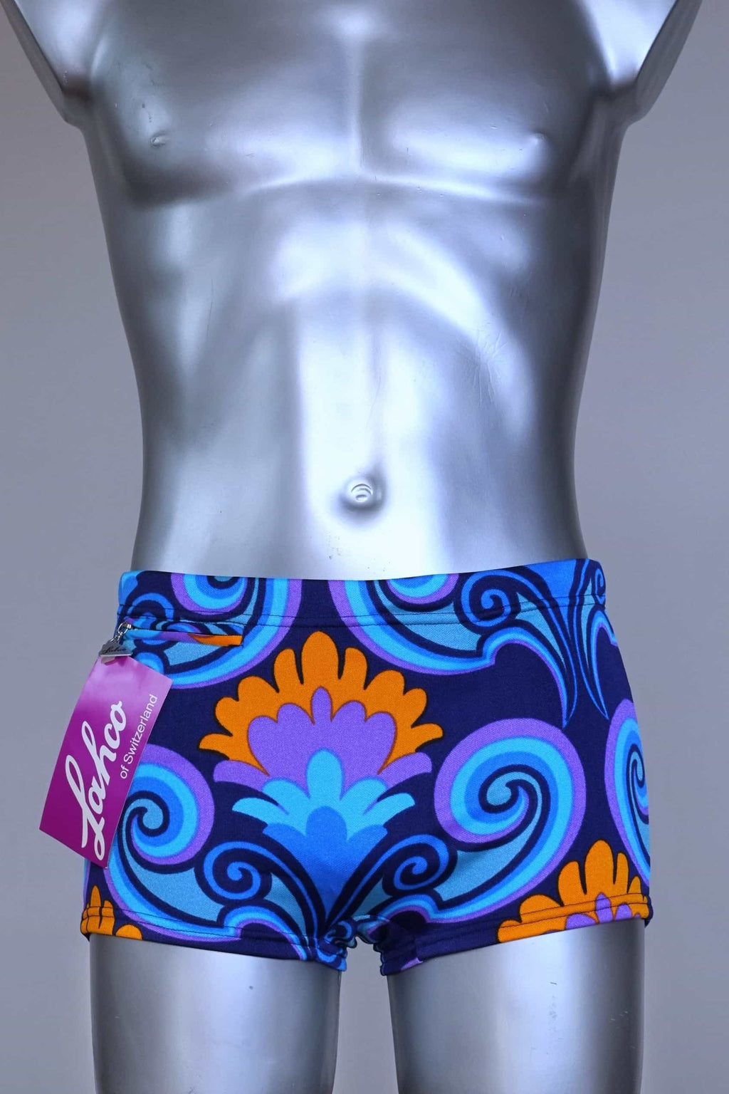 Front view of LAHCO vintage 60s square-cut swim trunks in a blue, purple, and orange psychedelic print, shown on a mannequin with original tag.