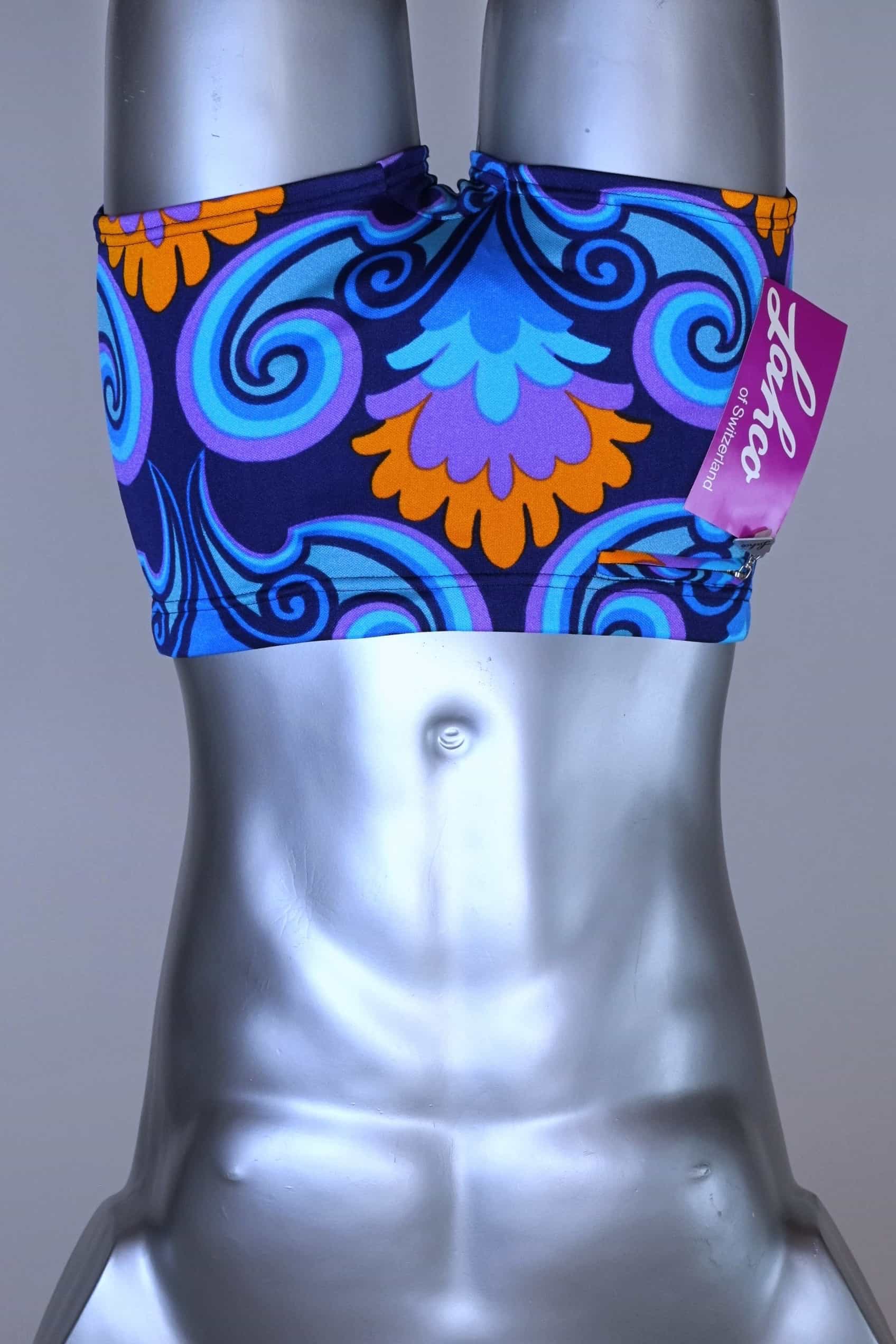 Front view of LAHCO vintage 60s square-cut swim trunks in a blue, purple, and orange psychedelic print, shown on a mannequin with original tag.
