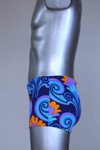 Side view of LAHCO vintage 60s square-cut swim trunks in a blue, purple, and orange psychedelic floral print, shown on a mannequin with original tag.