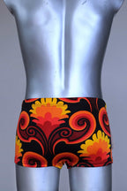 Back view of LAHCO vintage 60s square-cut swim trunks in a red, orange, and yellow psychedelic floral print, shown on a mannequin with original tag.