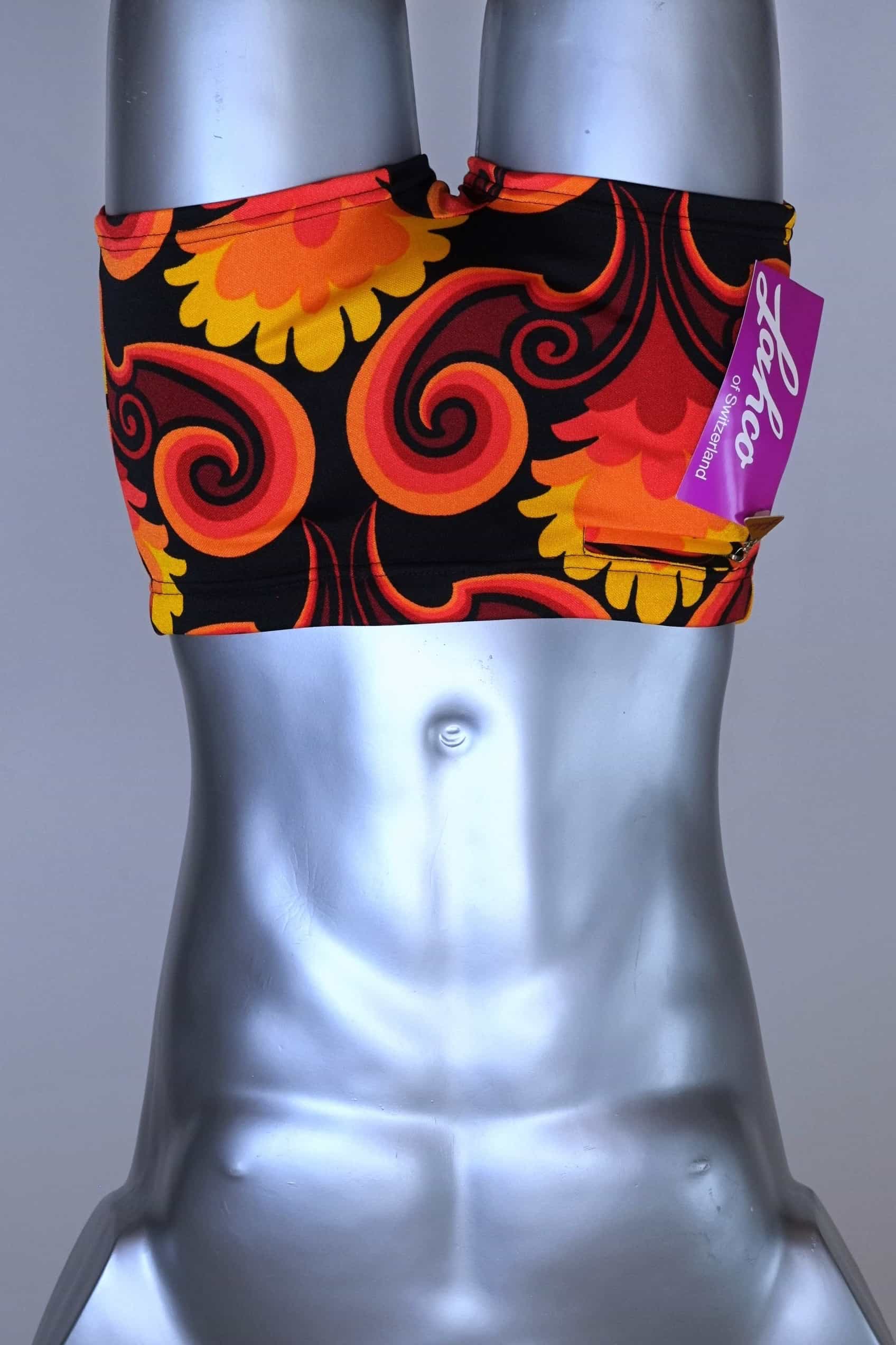Front view of LAHCO vintage 60s square-cut swim trunks in a red, orange, and yellow psychedelic print, shown on a mannequin with original tag.