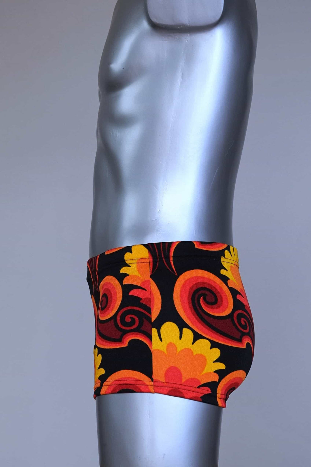Side view of LAHCO vintage 60s square-cut swim trunks in a red, orange, and yellow psychedelic floral print, shown on a mannequin with original tag.