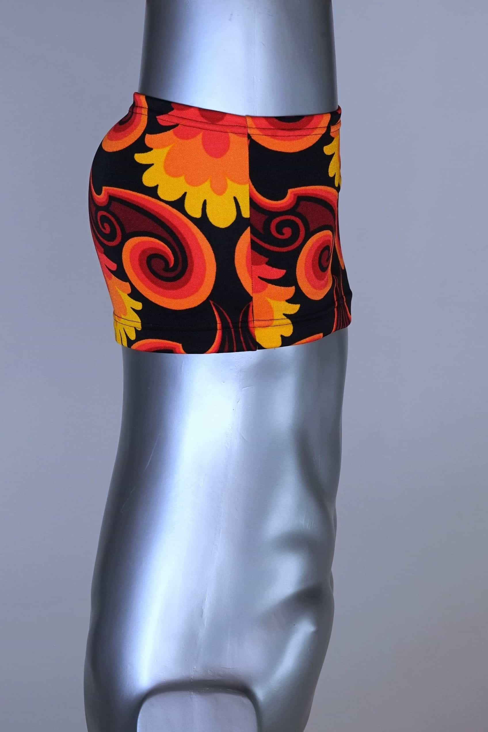 Side view of LAHCO vintage 60s square-cut swim trunks in a red, orange, and yellow psychedelic floral print, shown on a mannequin with original tag.