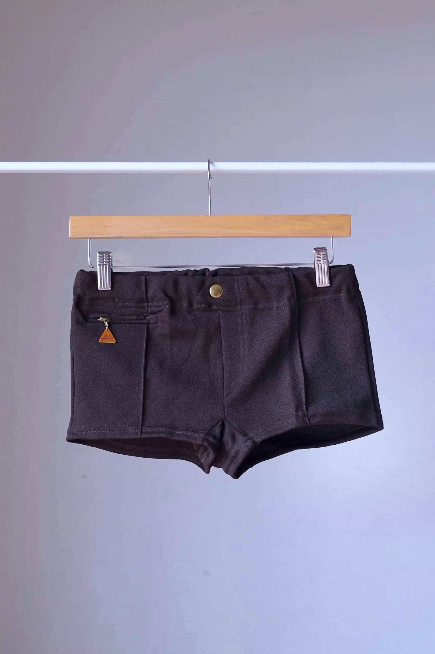 Brown Vintage 60s Lahco Mataro model swim trunks on hanger, showing structured waistband and minimalist design.