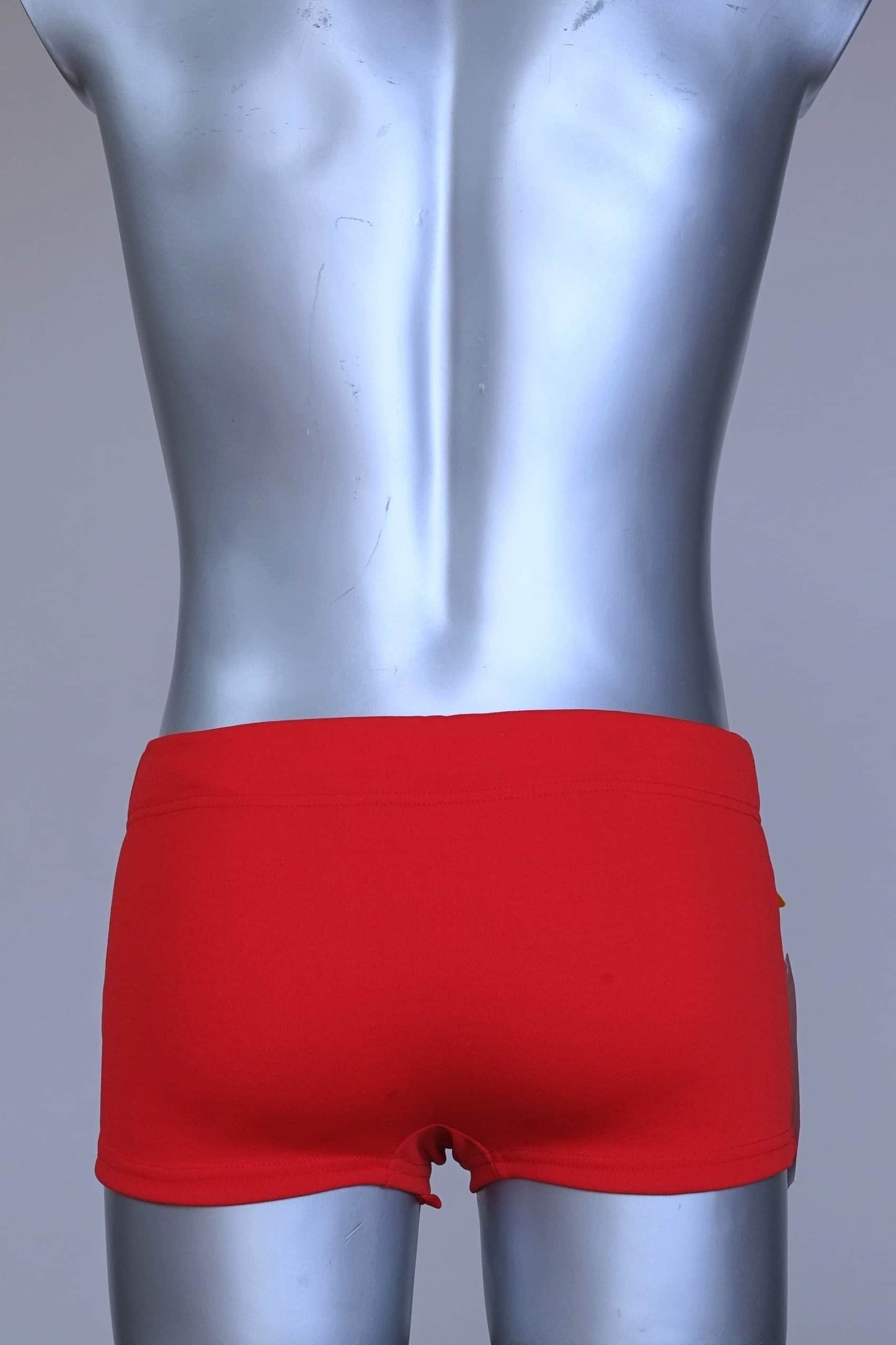 Back view of red Lahco vintage 60s swim trunks (Mataro model) on silver mannequin, showing zip pocket and snap waistband.