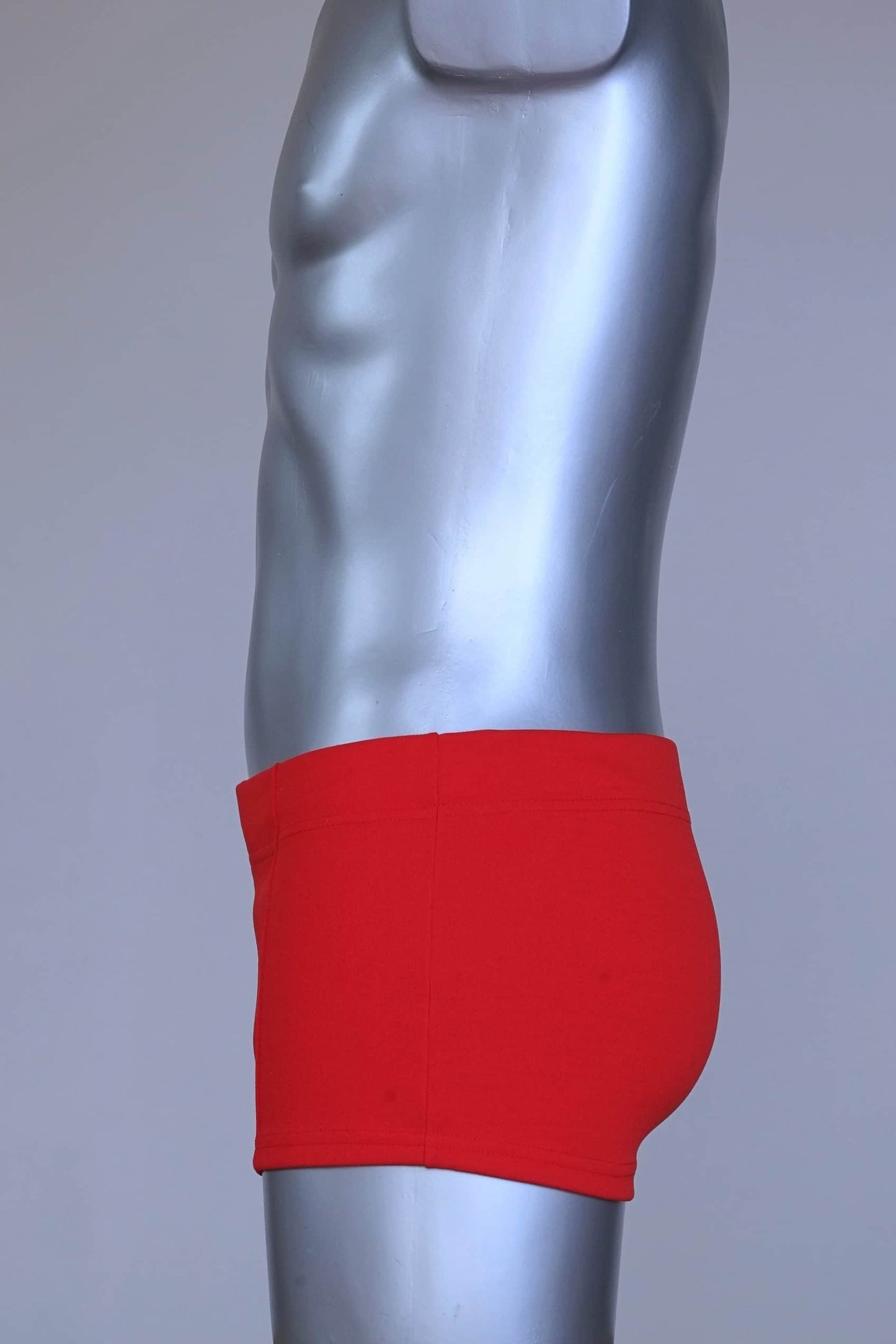 Side view of red Lahco vintage 60s swim trunks (Mataro model) on silver mannequin, showing zip pocket and snap waistband.