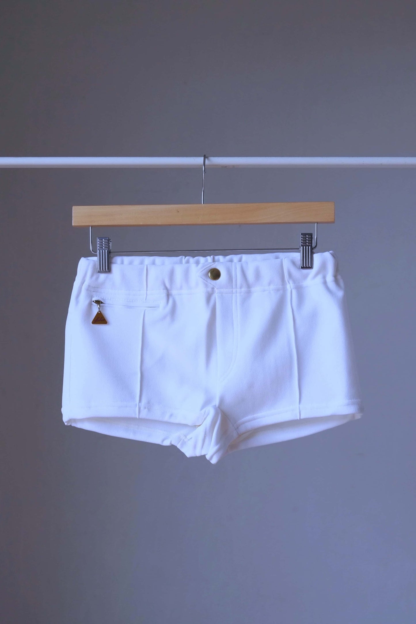 White Vintage 60s Lahco Mataro model swim trunks on hanger, showing structured waistband and minimalist design.