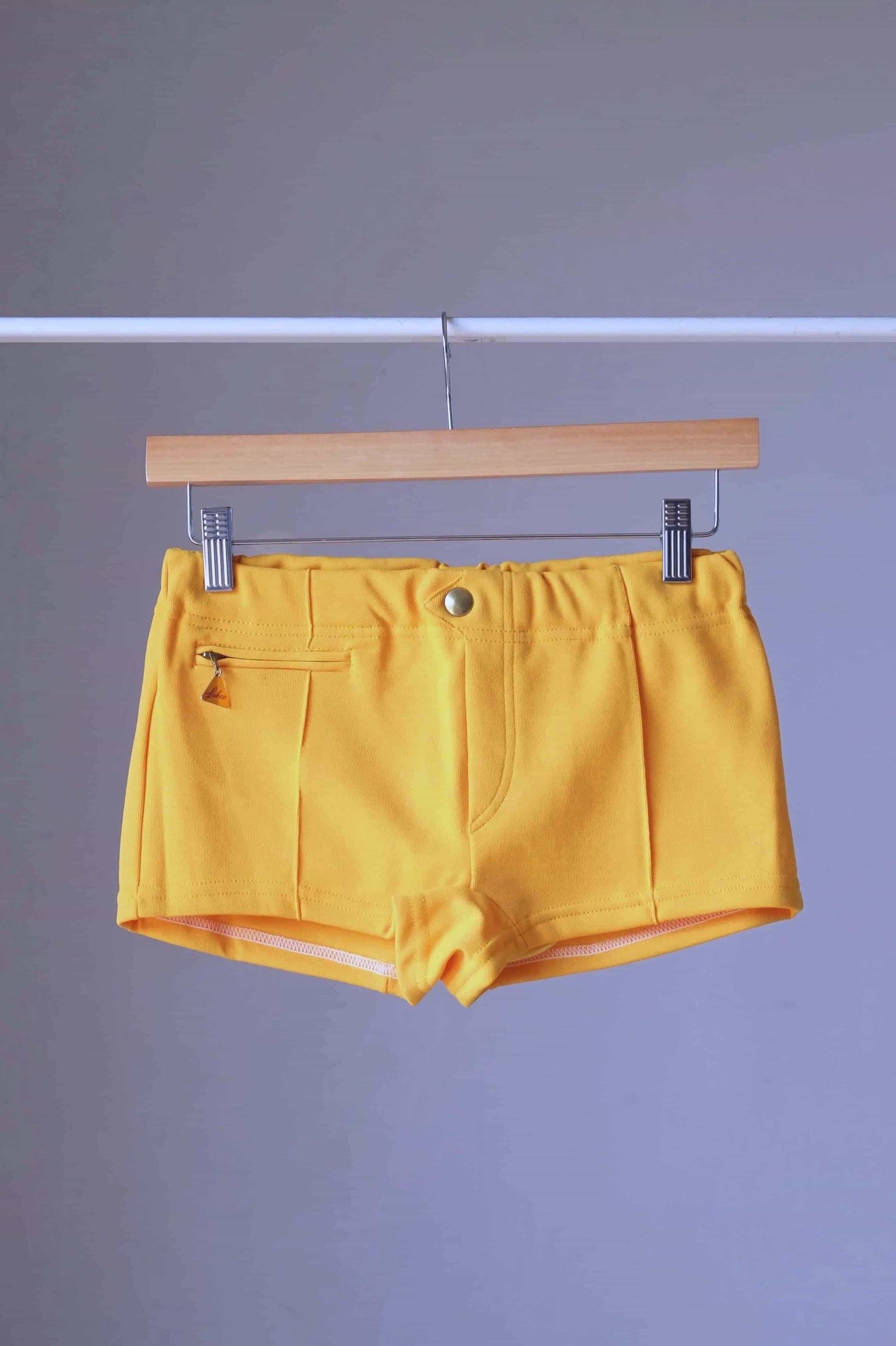Yellow Vintage 60s Lahco Mataro model swim trunks on hanger, showing structured waistband and minimalist design.
