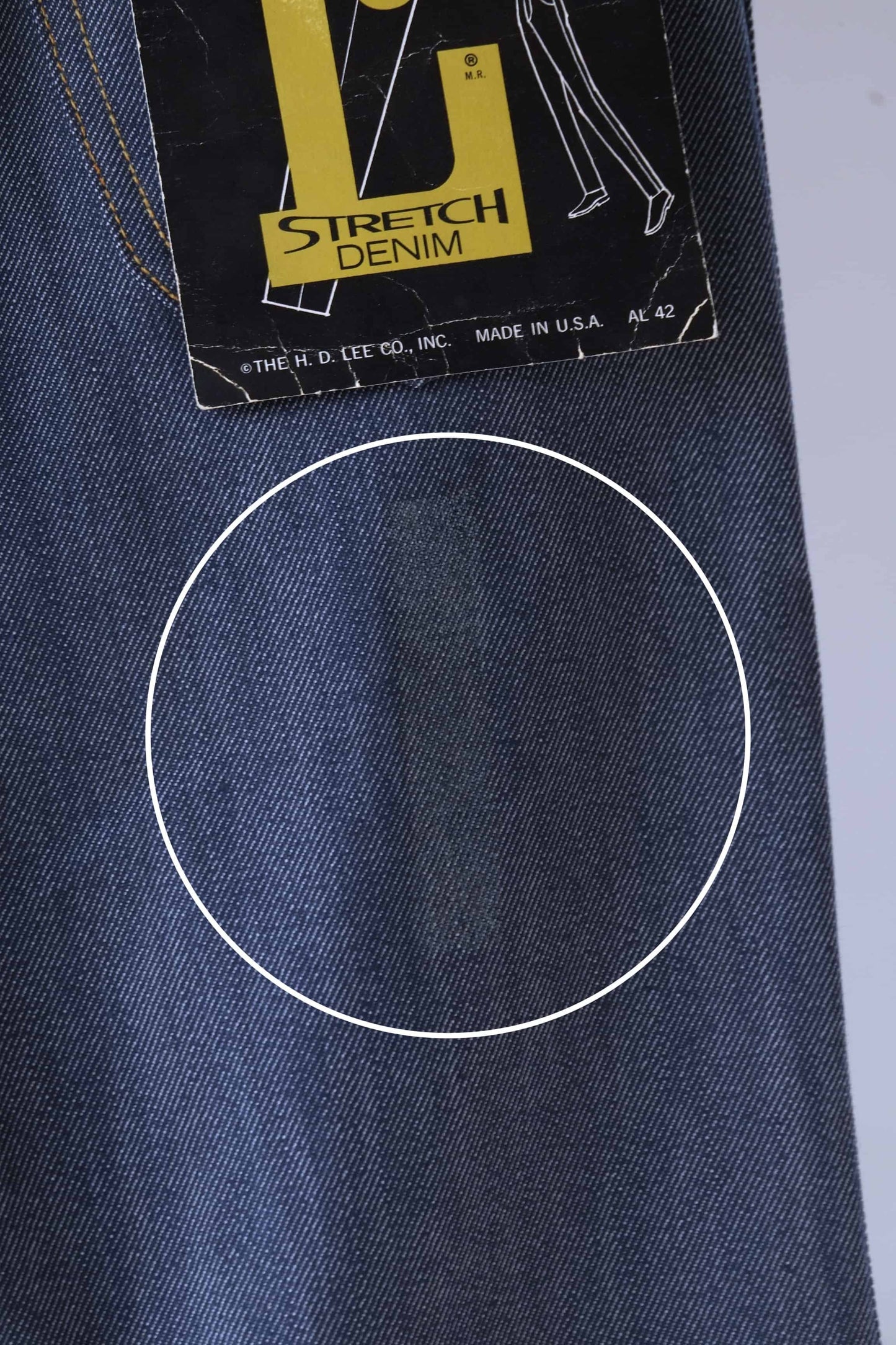 Close shot of a circled stain on the back of a pair of Lee lastic vintage denim jeans
