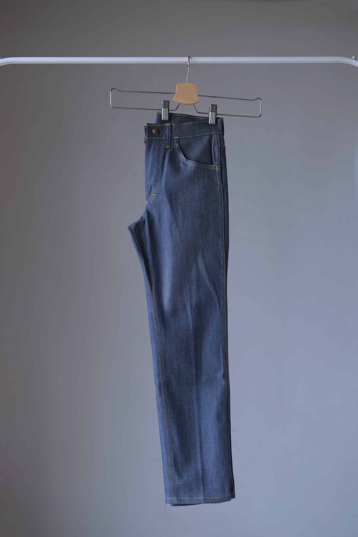 Side view of a pair of Vintage Lee lastic stretch denim jeans on hanger