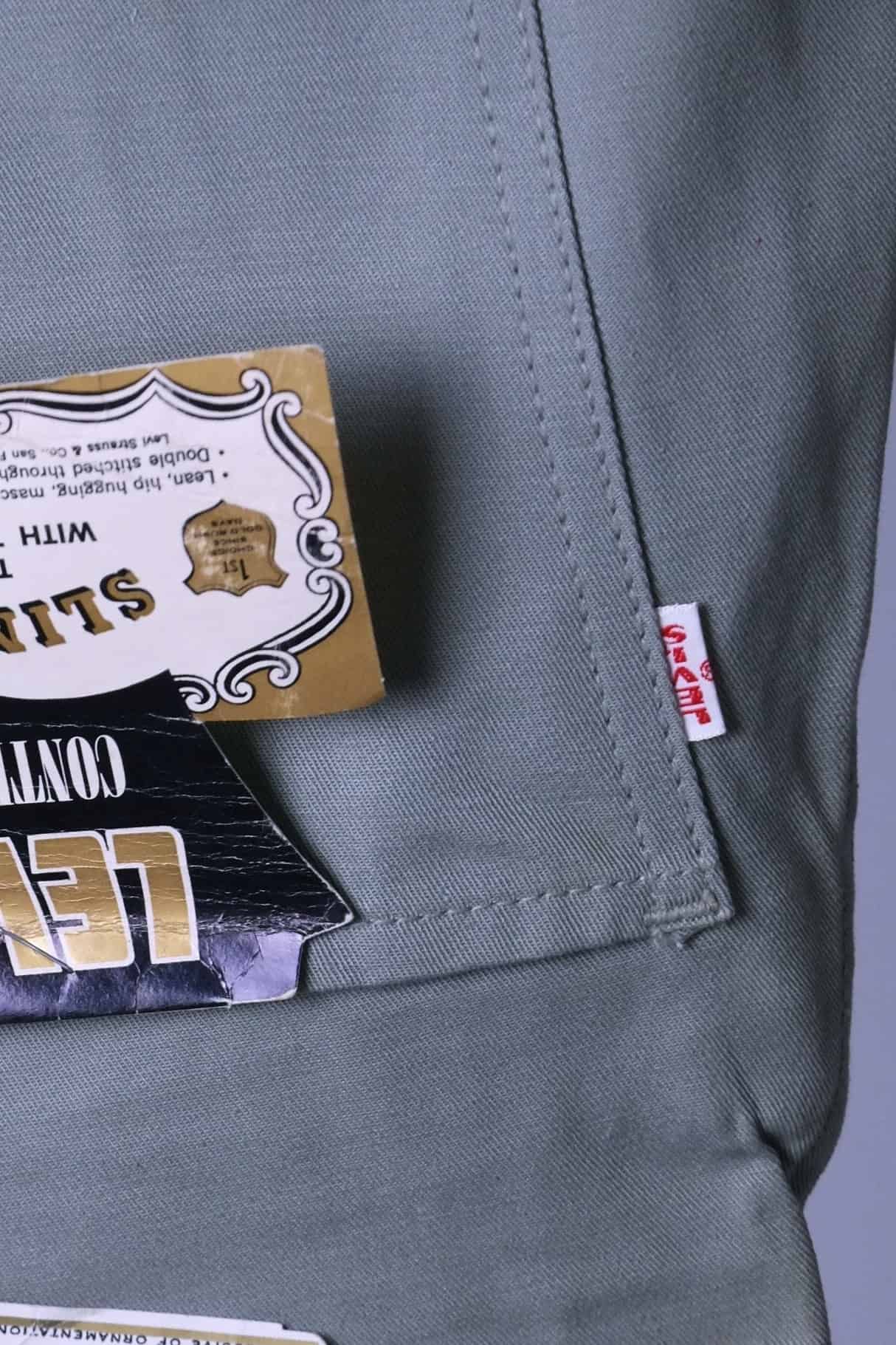 Extreme close-up of the white Big E red tab on the back pocket of the 1960s Levi's Continental trousers (sage color).