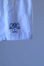 Close-up of the embroidered geometric "Big Point by Löffler" logo on white vintage 90s Tactel nylon tennis shorts.