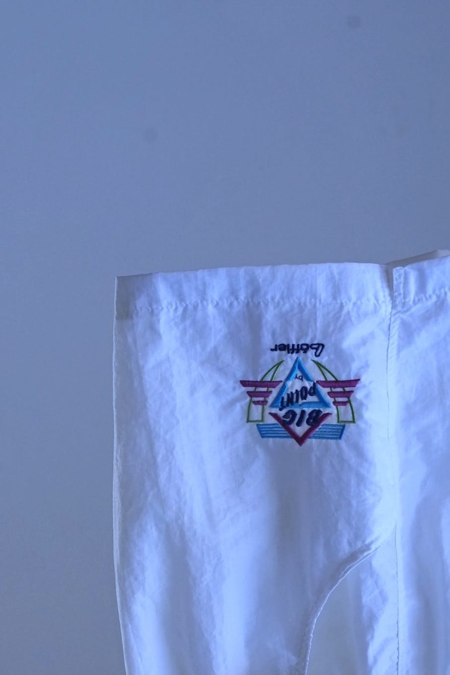 Close-up of the embroidered geometric "Big Point by Löffler" logo on white vintage 90s Tactel nylon tennis shorts.