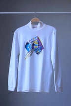 Front view of white Löffler 90s mock neck long-sleeve tennis top with a mustard, blue and purple “Start the Craze” graphic and Transtex collar embroidery