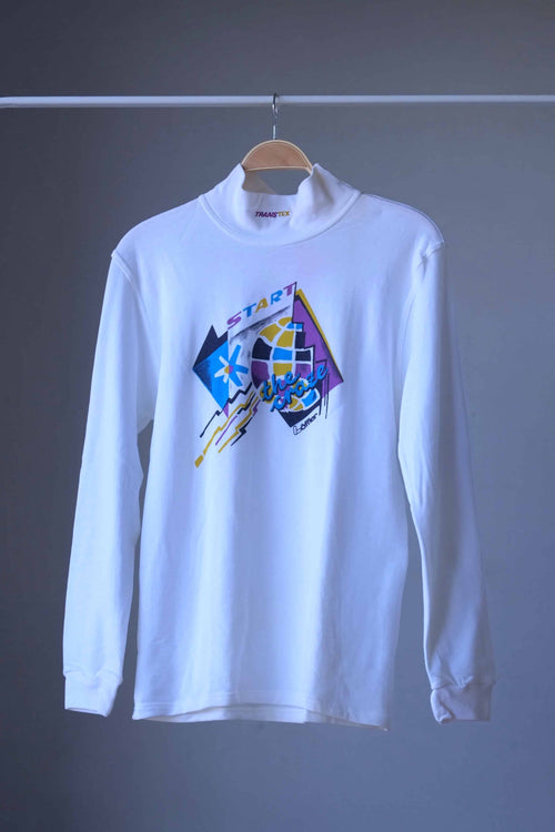 Front view of white Löffler 90s mock neck long-sleeve tennis top with a mustard, blue and purple “Start the Craze” graphic and Transtex collar embroidery