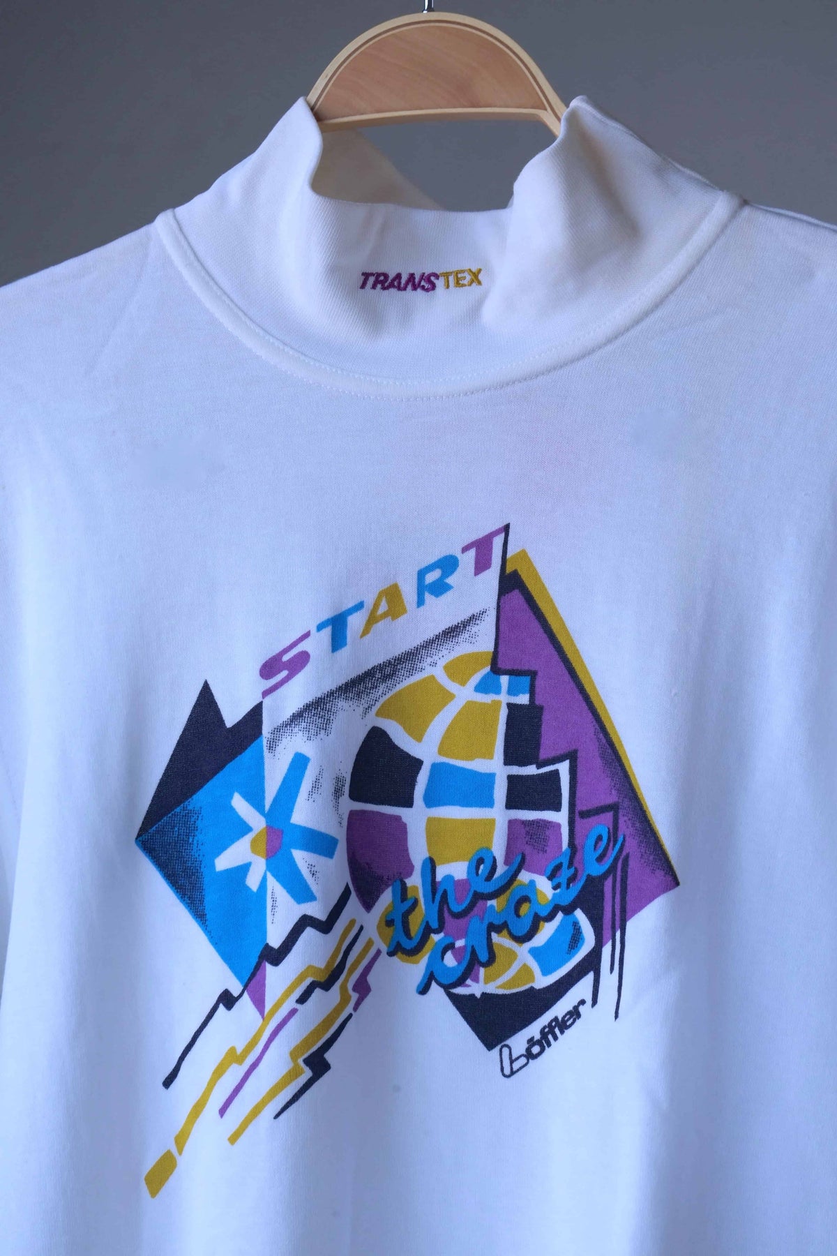 Close-up of the mock neck collar with yellow and purple Transtex embroidery above the yellow, blue and purple “Start the Craze” graphic