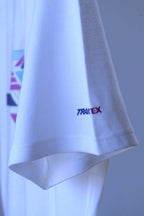 A close-up of a vintage Löffler white polo shirt sleeve featuring a small embroidered logo that reads 'Transtex' in blue and purple, set against a matching white shirt background.