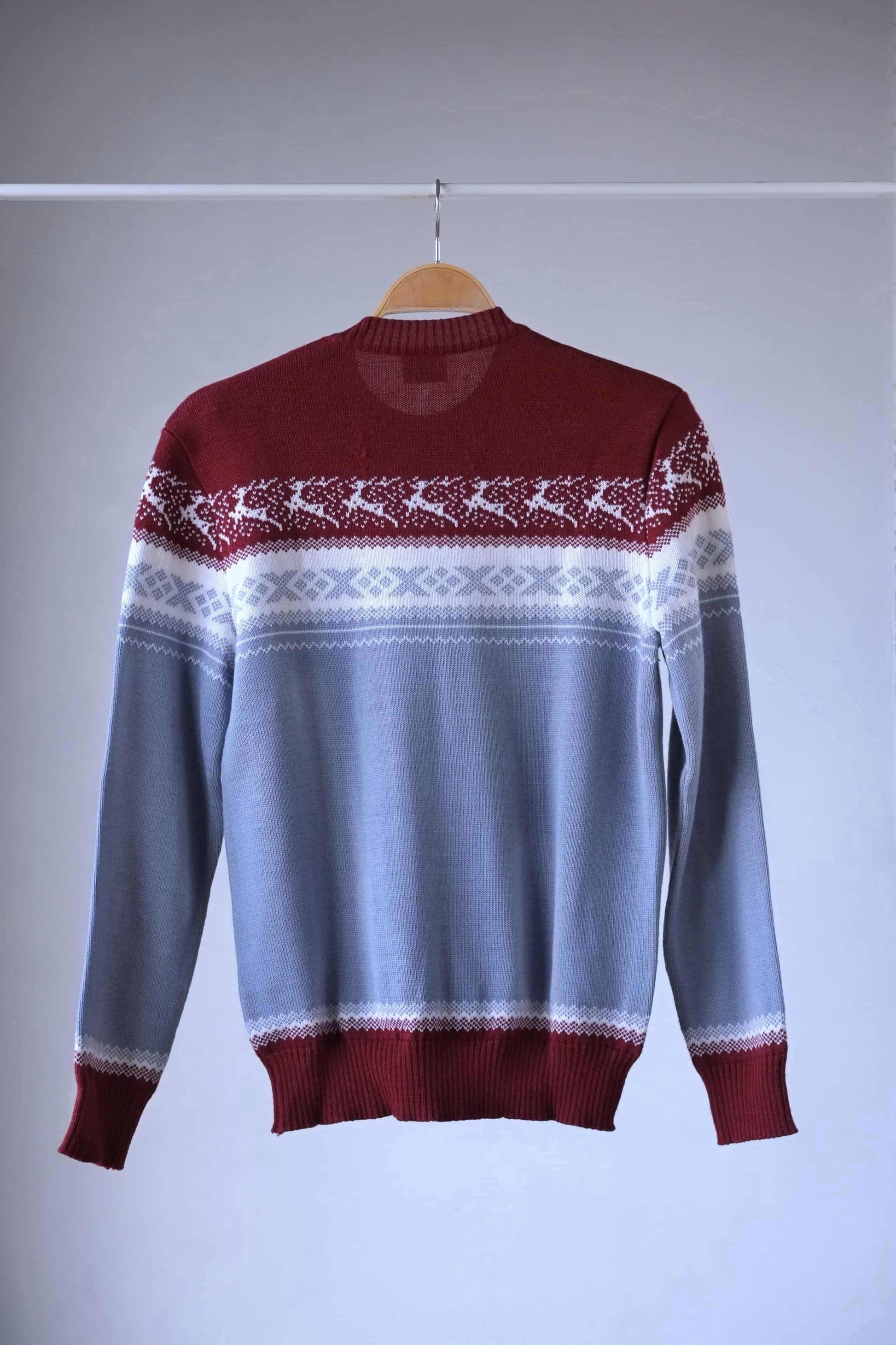 Back view of Löffler brand burgundy and gray wool blend sweater featuring a white Nordic pattern with reindeer and snowflake motifs, hanging on a wooden hanger against a plain background.