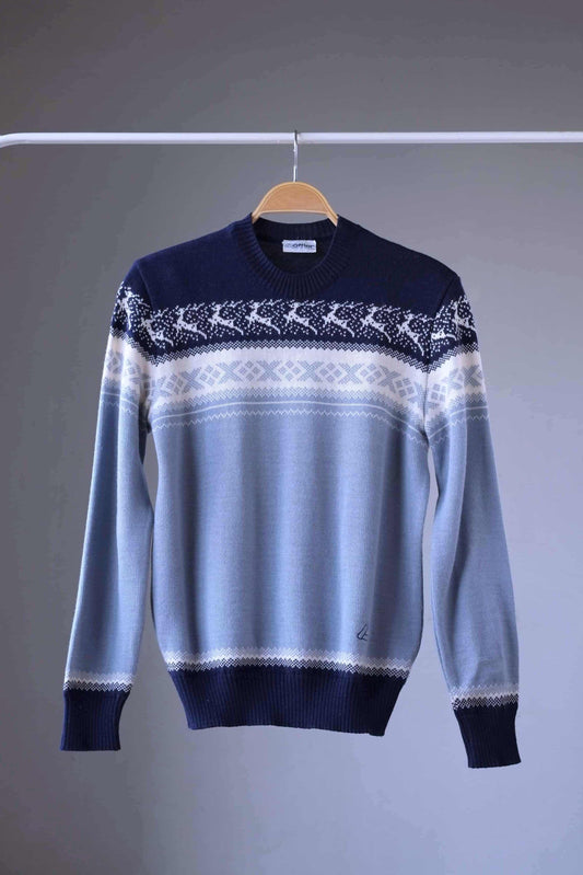 Löffler brand navy and light blue wool blend sweater featuring a white Nordic pattern with reindeer and snowflake motifs, hanging on a wooden hanger against a plain background.