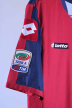 Close-up of the short sleeve on the jersey, showcasing an embroidered rectangular "lotto" patch on a red background and a stitched Serie A TIM league patch lower on the navy sleeve.