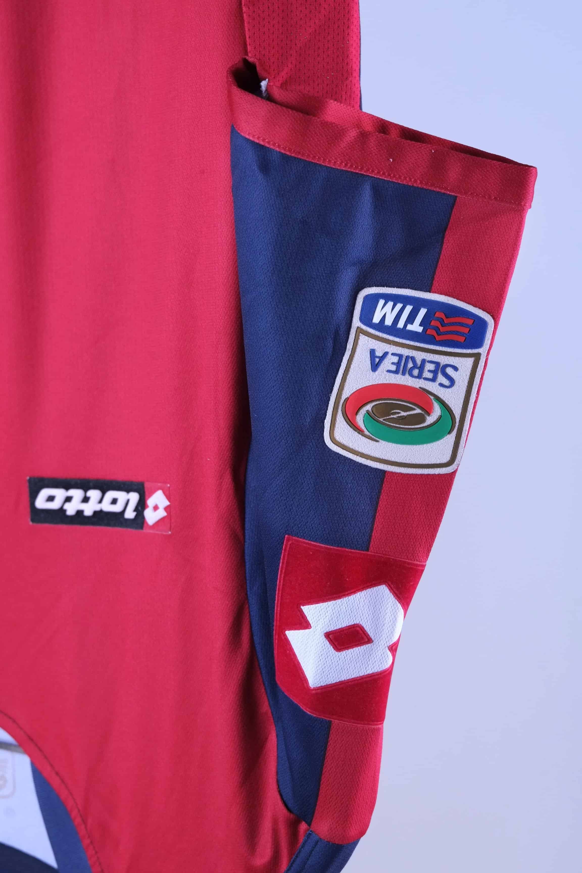 Close-up of the short sleeve on the jersey, showcasing an embroidered rectangular "lotto" patch on a red background and a stitched Serie A TIM league patch lower on the navy sleeve.