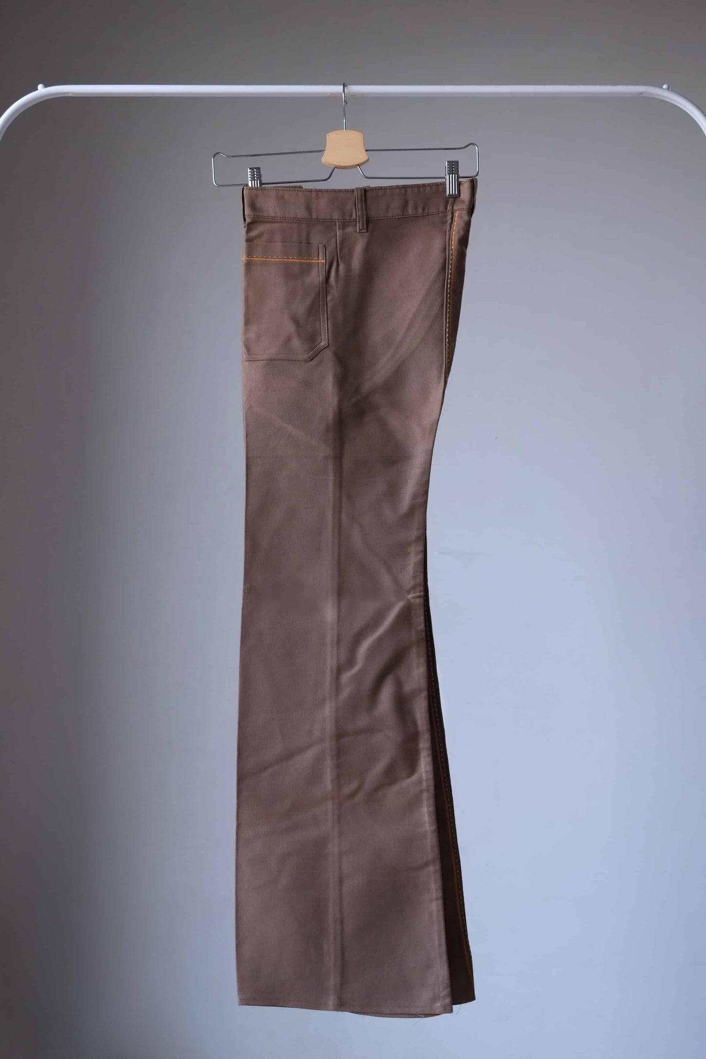 Lucky Paris 70's Vintage brown-colored flared pants hanging on a hanger. The pants have a wide leg opening and feature an orange-colored stitching detail.