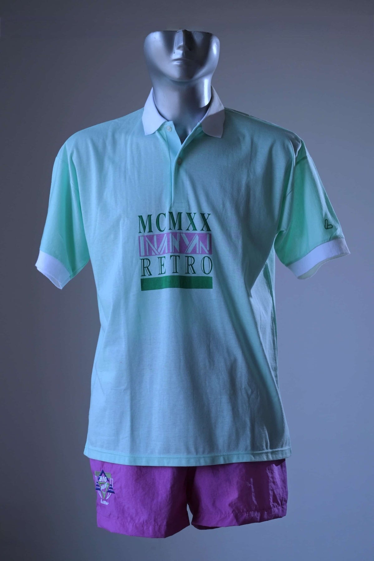 Front view of mint green Löffler 90s men’s tennis polo on a mannequin with white collar and cuffs, styled with purple Löffler shorts