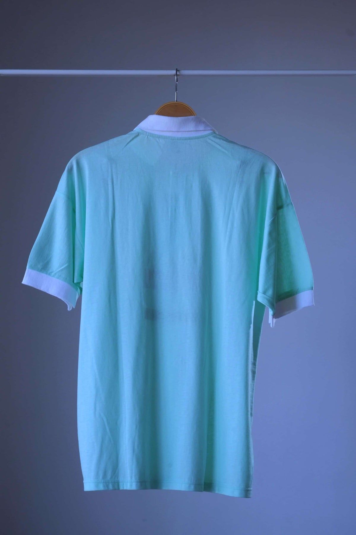 Back view of mint green Löffler 90s men’s short-sleeve polo with white collar and white ribbed cuffs, plain back with no print