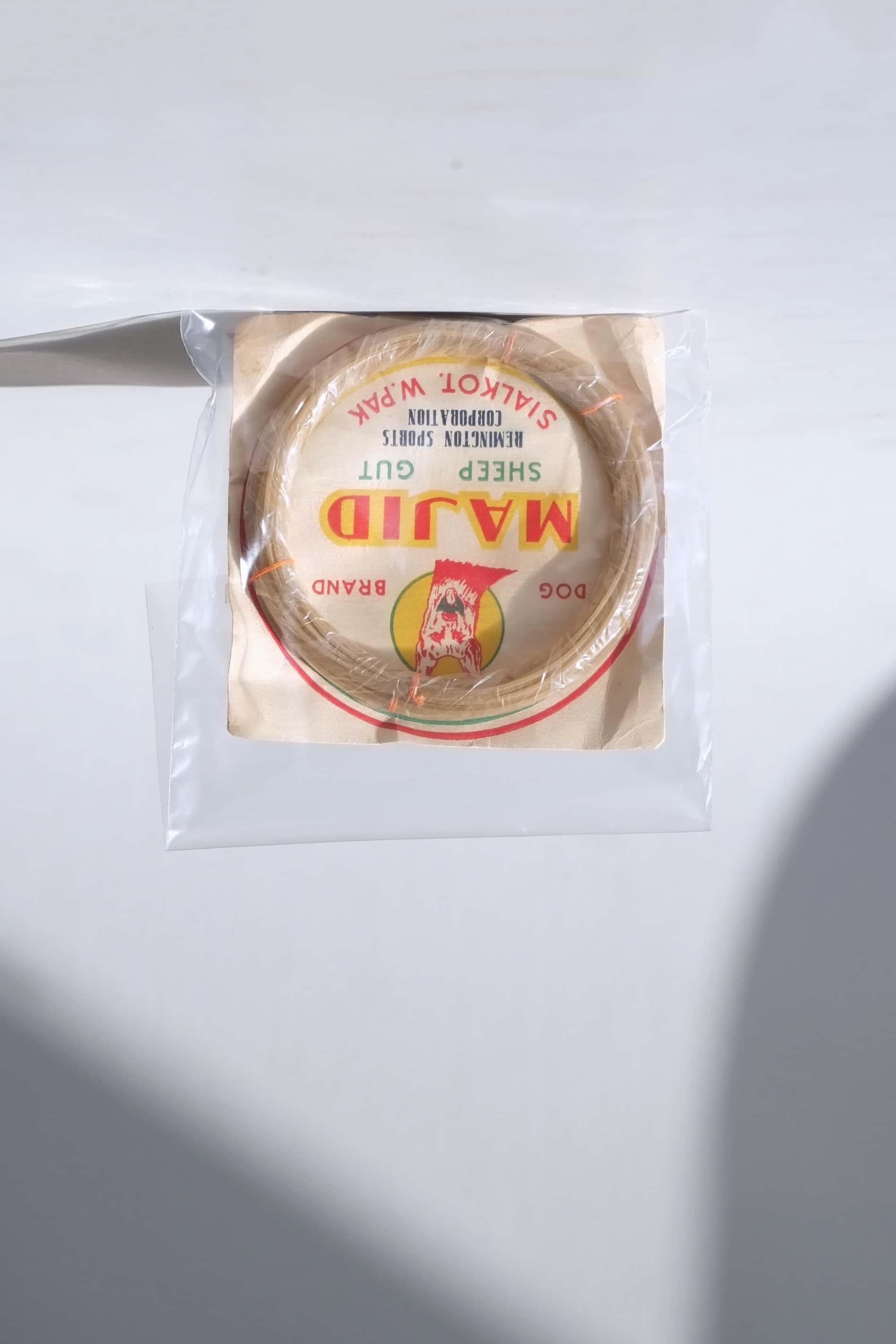 Vintage pre-1971 Majid Dog Brand organic sheep gut racket strings, sealed inside a protective clear collector's sleeve.